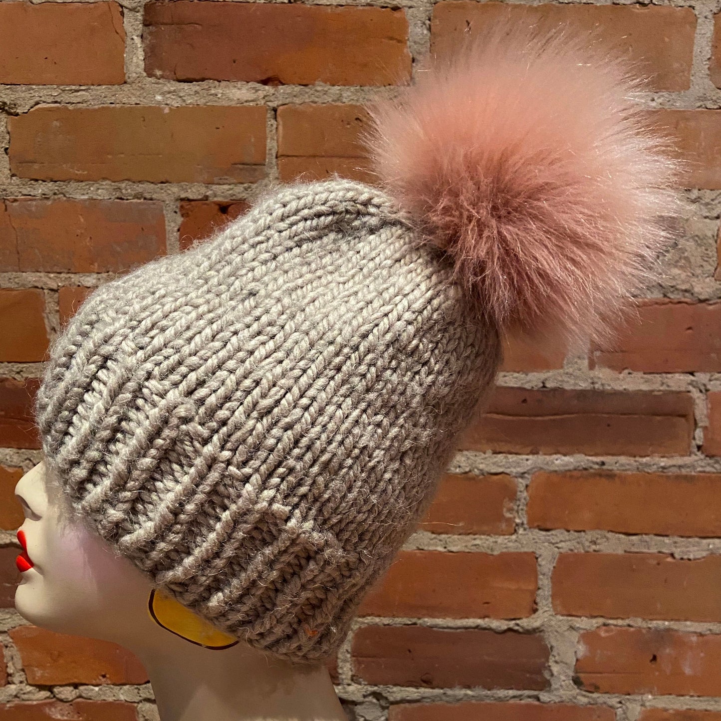 side view of Jumbo Pink Faux Fur pom pom on beige knit hat