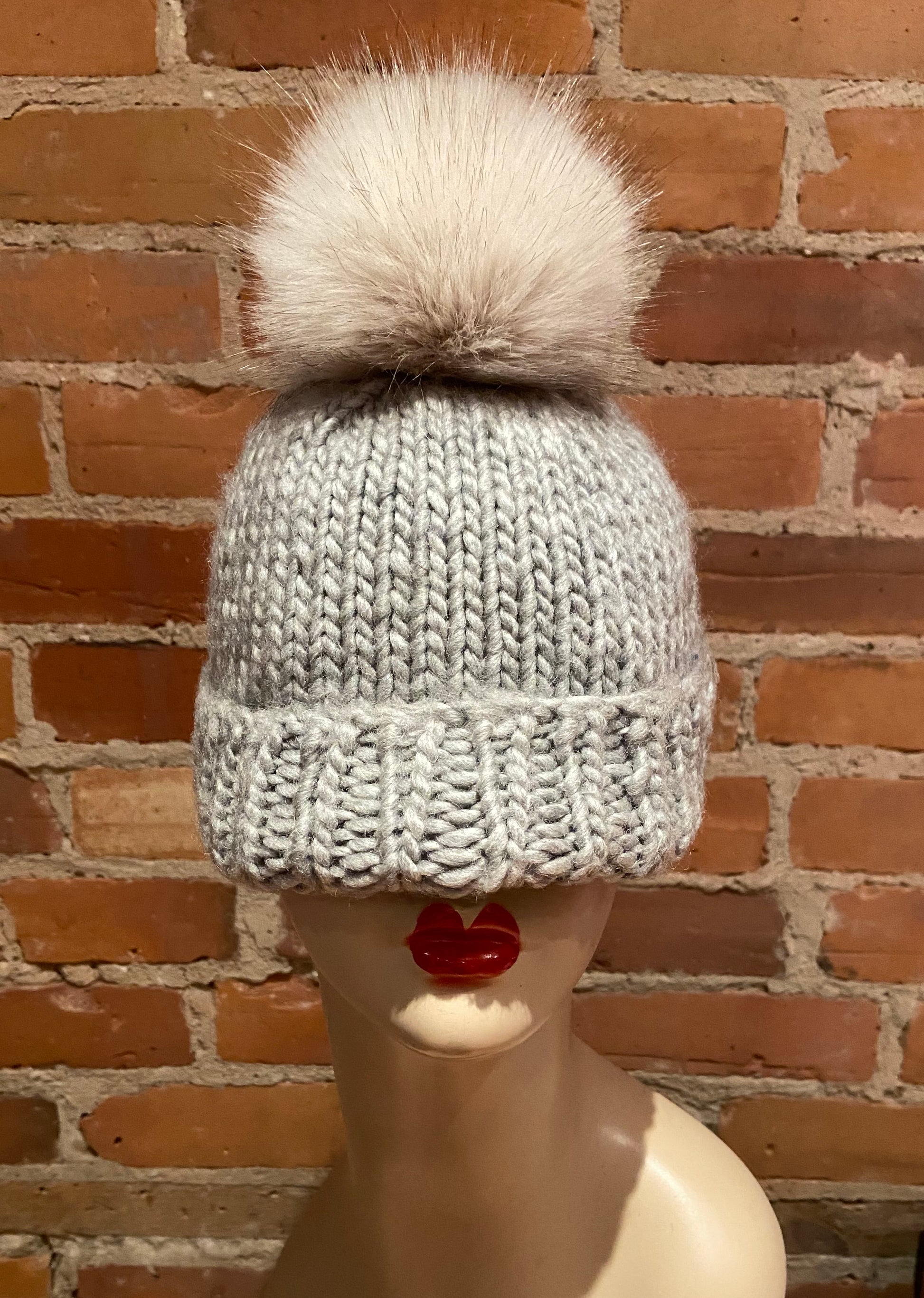 Beige Hat Pom attached to a grey knit hat
